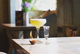 Image of the inside of The Tipsy Bird bar showing a drink on a table 